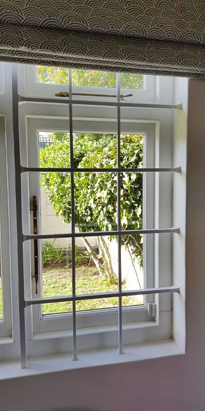 White grid-pattern grille with garden view beneath a patterned pelmet