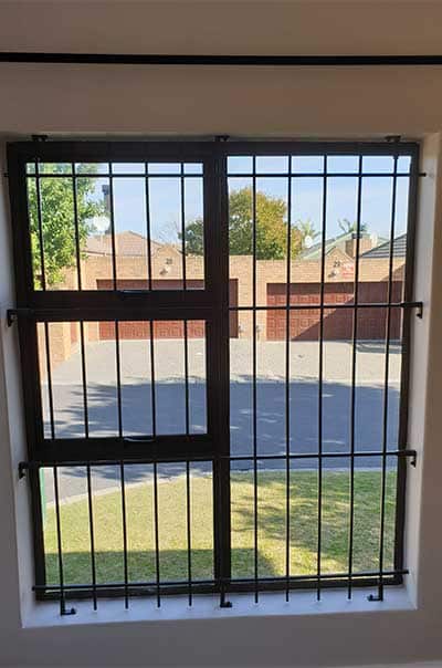 Black Mini Spanish burglar bars in vertical style with brick townhouse view outside