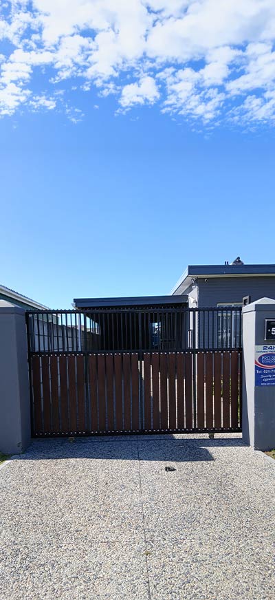 Black driveway security barrier between brick entrance pillars