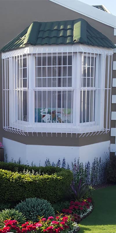 White wrought-iron grille on bay window with garden