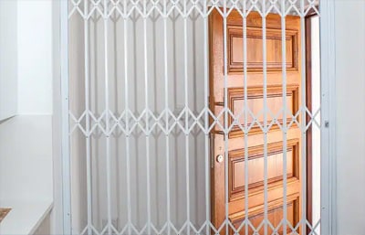 White diamond-pattern Magnador Standard retractable grille beside a wooden front door