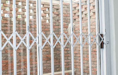 White diamond-pattern Valuedor retractable grille against a decorative brick wall