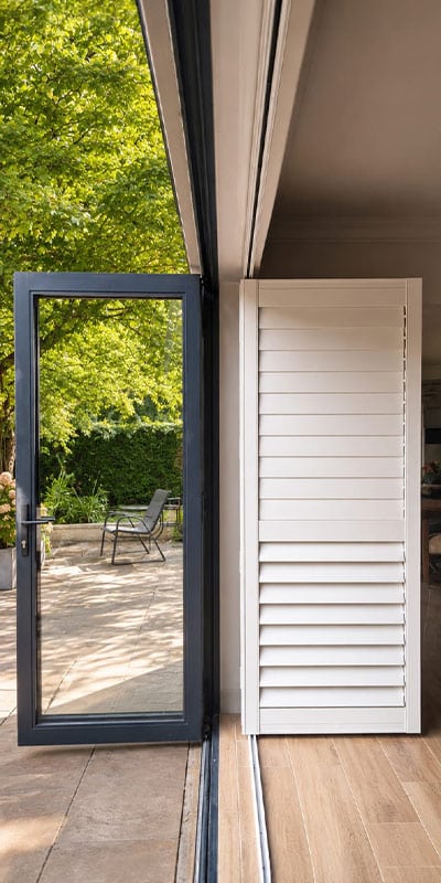 Shutterstyle gate open beside glass door to garden